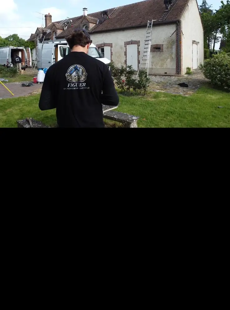 Artisan FIGUIER en tenue floquée, de dos, sur un chantier de réfection de toiture